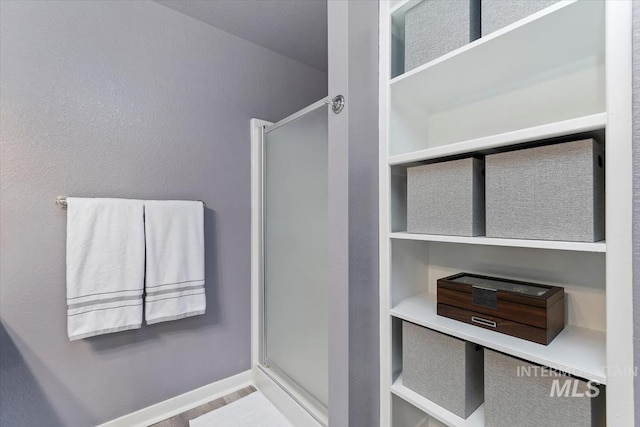 full bath with baseboards and a stall shower