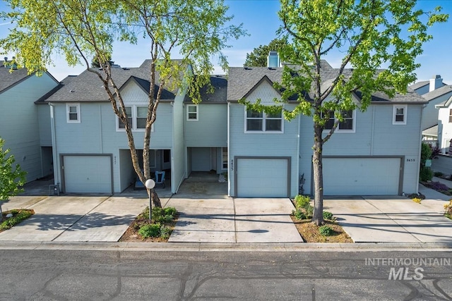 multi unit property featuring a garage, driveway, a residential view, and a shingled roof