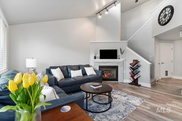 living room with baseboards, wood finished floors, high vaulted ceiling, and a fireplace