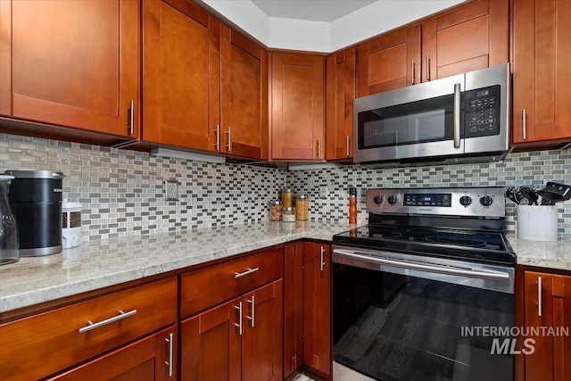 kitchen with backsplash, stainless steel appliances, brown cabinets, and light stone counters