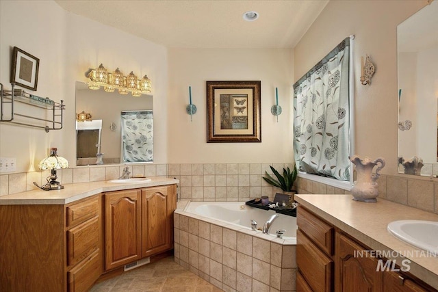 bathroom with tile patterned flooring, vanity, and a relaxing tiled tub