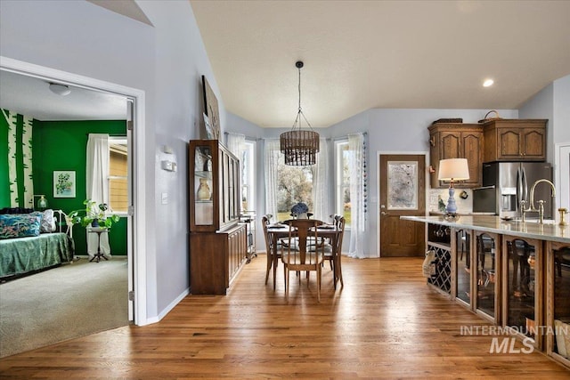 kitchen with hanging light fixtures, sink, hardwood / wood-style floors, and stainless steel fridge with ice dispenser