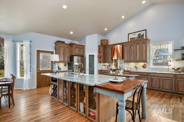 kitchen featuring vaulted ceiling, sink, a center island with sink, and decorative backsplash