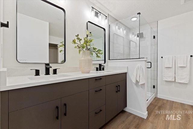 2007 S Makar Ln, Boise, ID 83706 - bathroom featuring wood finished floors, double vanity, a stall shower, baseboards, and a textured ceiling