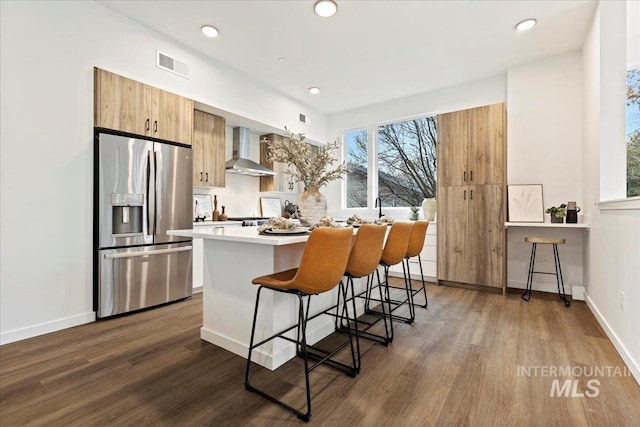 2007 S Makar Ln, Boise, ID 83706 - kitchen featuring stainless steel refrigerator with ice dispenser, wall chimney range hood, a center island, dark wood-type flooring, and a kitchen bar