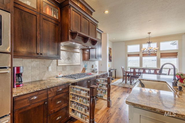 kitchen featuring a notable chandelier, glass insert cabinets, tasteful backsplash, and a sink