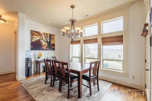 dining room with a chandelier, baseboards, visible vents, and wood finished floors