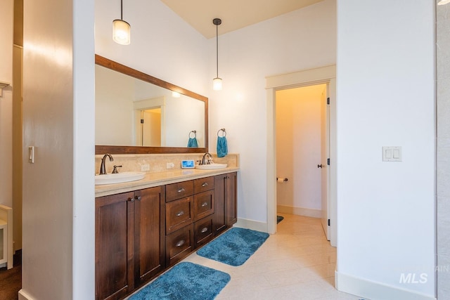 full bath featuring a sink, baseboards, and double vanity