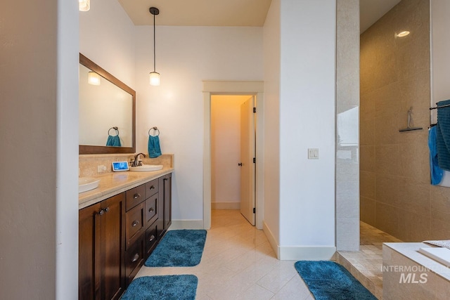 bathroom featuring tile patterned flooring, a walk in shower, baseboards, double vanity, and a sink