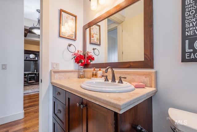 half bath with vanity, toilet, and wood finished floors