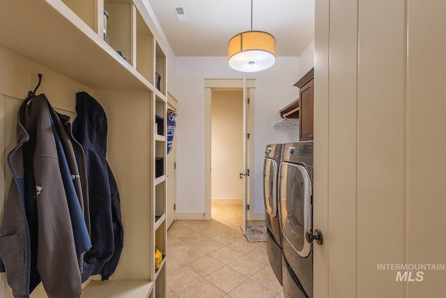 clothes washing area featuring light tile patterned floors, visible vents, baseboards, cabinet space, and washing machine and dryer