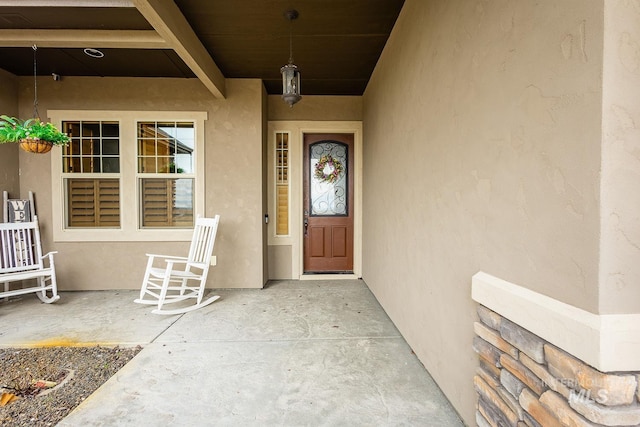 view of exterior entry featuring a porch and stucco siding