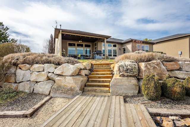 back of property with stucco siding and a ceiling fan