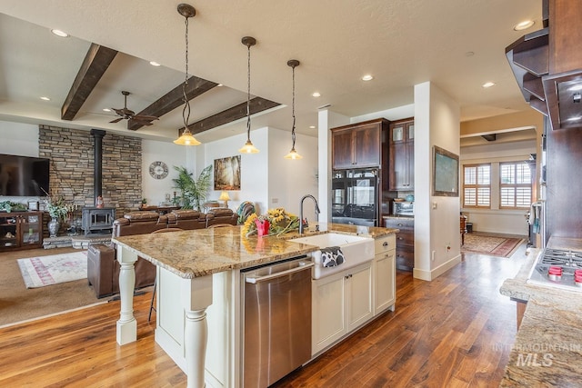 kitchen with light wood-style flooring, a sink, open floor plan, dishwasher, and a wood stove