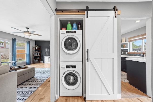 2906 W Kathryn St, Boise, ID 83705 - washroom featuring stacked washing machine and dryer, a barn door, light wood-style floors, and a ceiling fan