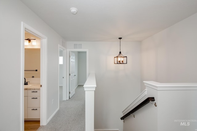 corridor with light carpet and an inviting chandelier