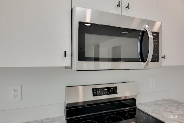 details with white cabinetry, light stone counters, and stainless steel appliances