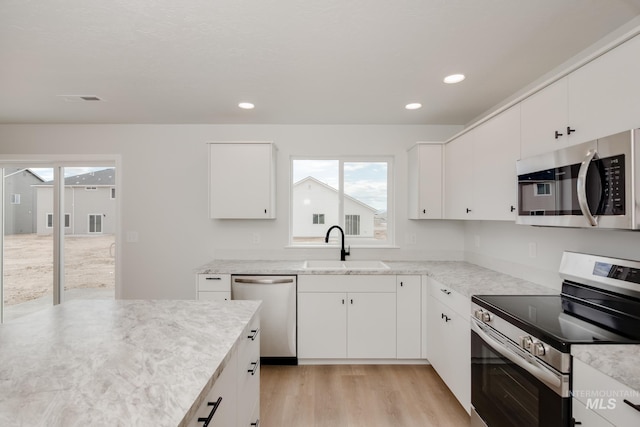 kitchen featuring white cabinetry, appliances with stainless steel finishes, sink, and light wood-type flooring