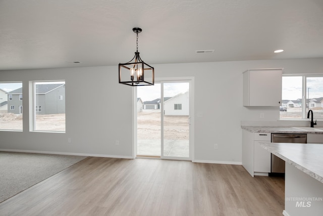 unfurnished dining area with sink, a chandelier, and light hardwood / wood-style floors