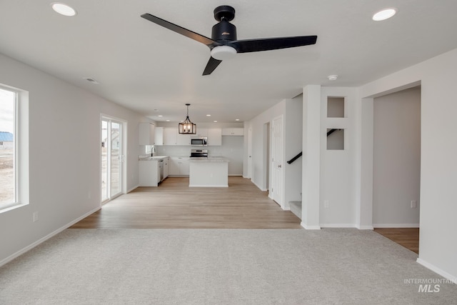 unfurnished living room with ceiling fan and light colored carpet