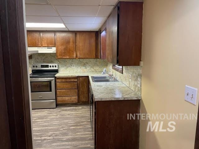 271 Tyler St, Twin Falls, ID 83301 - kitchen featuring stainless steel range with electric cooktop, under cabinet range hood, light wood-style flooring, light countertops, and backsplash