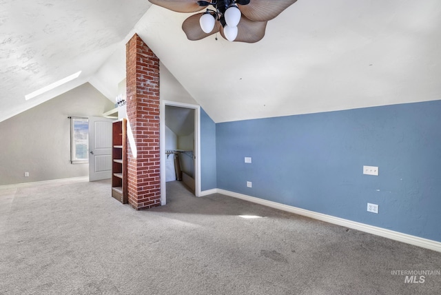 bonus room featuring lofted ceiling with skylight, carpet flooring, ceiling fan, and baseboards