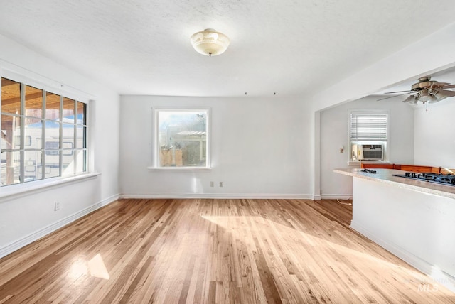 unfurnished living room with cooling unit, light wood-style flooring, and baseboards