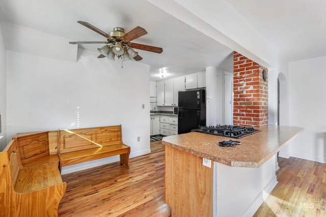 kitchen featuring ceiling fan, black appliances, light wood finished floors, and baseboards