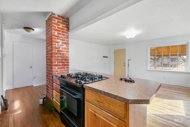 kitchen with black gas range oven, baseboards, and wood finished floors