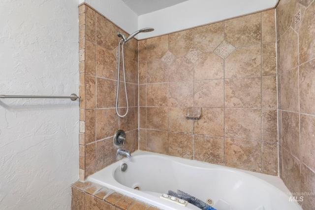 bathroom featuring a textured wall and tiled shower / bath combo