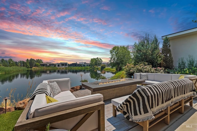 patio terrace at dusk featuring a water view and an outdoor living space with a fire pit