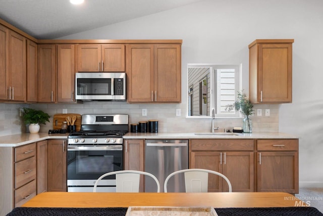 kitchen featuring vaulted ceiling, stainless steel appliances, sink, and backsplash