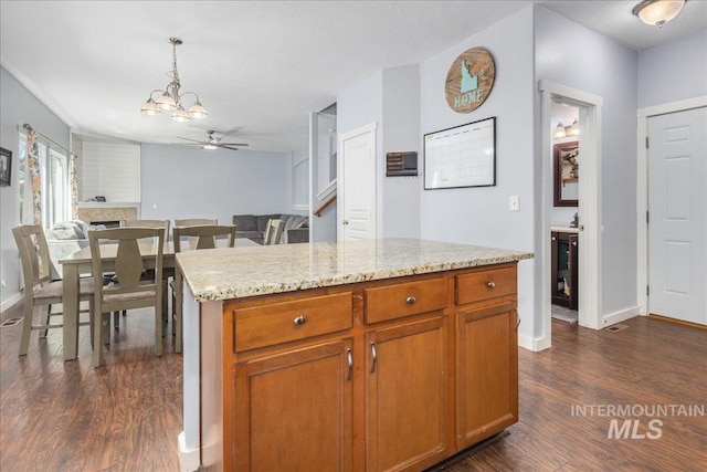 6495 S Mistyglen Ave, Boise, ID 83709 - kitchen with dark wood-style flooring, a ceiling fan, pendant lighting, and light stone counters