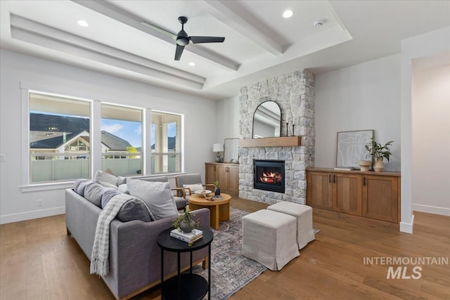 living room with a fireplace, light wood-type flooring, and ceiling fan