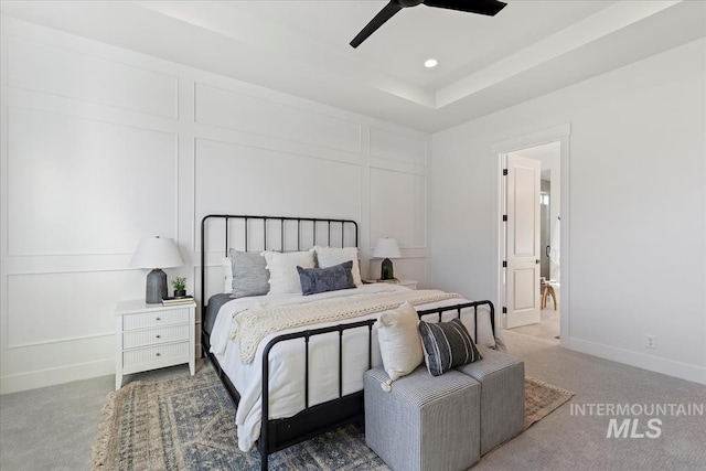 bedroom featuring ceiling fan, dark carpet, a raised ceiling, and ensuite bath