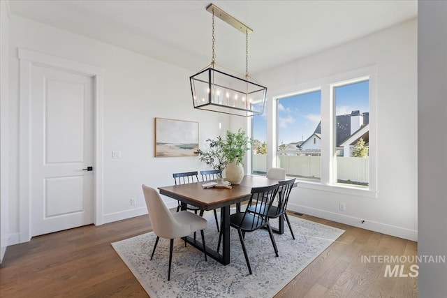 dining area with plenty of natural light, hardwood / wood-style floors, and an inviting chandelier