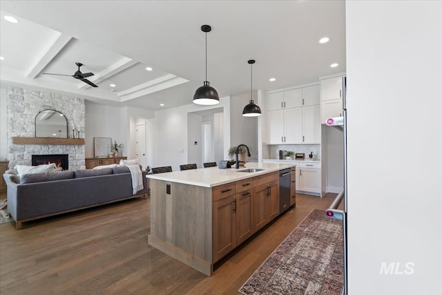 kitchen with pendant lighting, white cabinets, dishwasher, sink, and a center island with sink