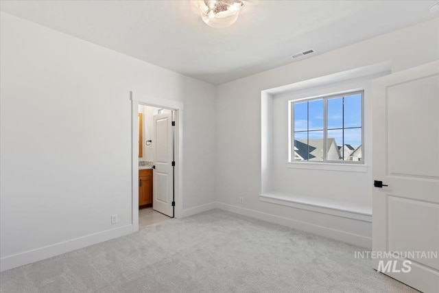 unfurnished bedroom with connected bathroom and light colored carpet