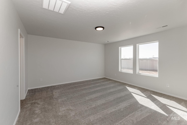 spare room with carpet flooring, visible vents, and baseboards