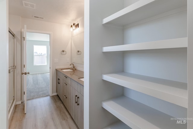 full bath featuring a sink, double vanity, visible vents, and wood finished floors