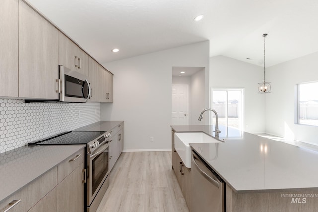 kitchen featuring light wood finished floors, a sink, light brown cabinets, appliances with stainless steel finishes, and lofted ceiling