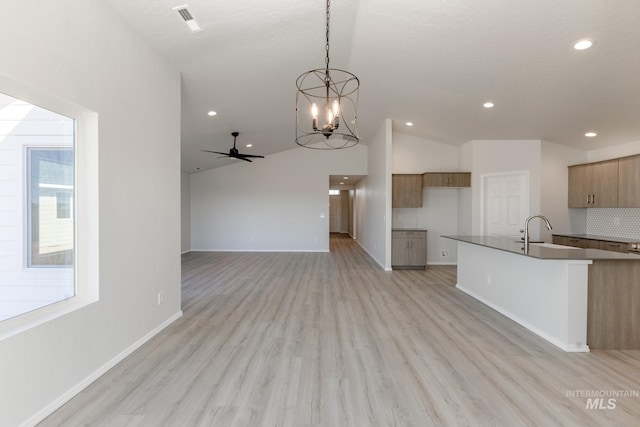 kitchen featuring a sink, lofted ceiling, ceiling fan with notable chandelier, and light wood-style floors