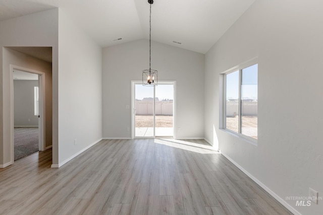 unfurnished dining area with vaulted ceiling, an inviting chandelier, baseboards, and wood finished floors