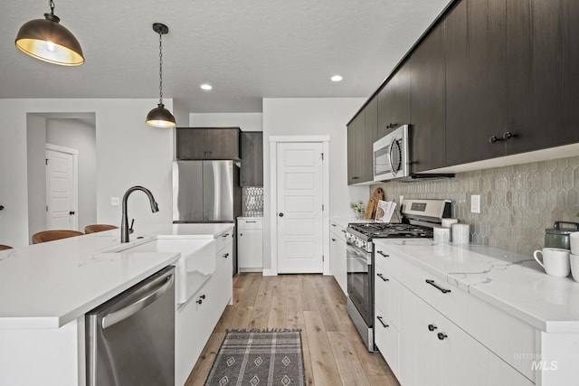 10061 W La Jolla Dr, Boise, ID 83709 - kitchen with appliances with stainless steel finishes, light wood finished floors, decorative backsplash, recessed lighting, and decorative light fixtures
