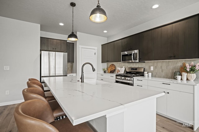 10061 W La Jolla Dr, Boise, ID 83709 - kitchen featuring appliances with stainless steel finishes, light wood finished floors, a kitchen breakfast bar, backsplash, and recessed lighting