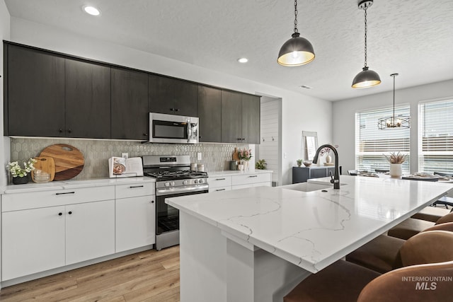 10061 W La Jolla Dr, Boise, ID 83709 - kitchen featuring appliances with stainless steel finishes, light wood-style flooring, a breakfast bar area, tasteful backsplash, and recessed lighting