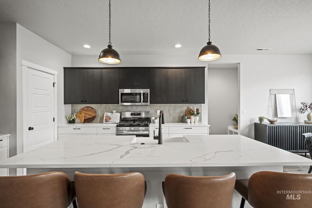 10061 W La Jolla Dr, Boise, ID 83709 - kitchen with stainless steel appliances, tasteful backsplash, an island with sink, a breakfast bar area, and recessed lighting