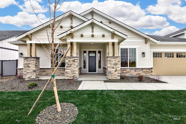 craftsman-style home featuring a front lawn, an attached garage, stone siding, and driveway