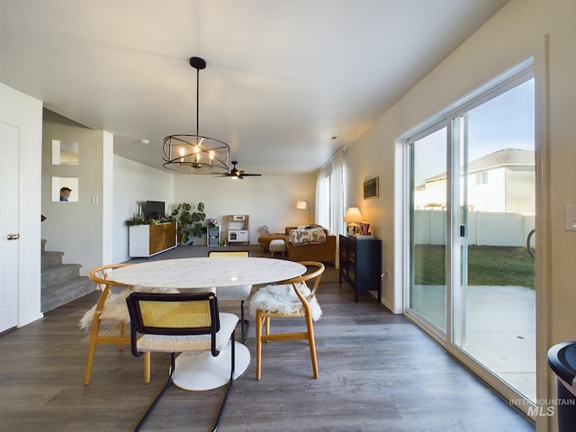 dining area featuring ceiling fan with notable chandelier and dark hardwood / wood-style floors