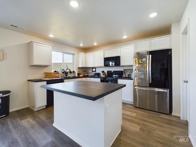 kitchen featuring white cabinets, a center island, dark wood-type flooring, and black appliances